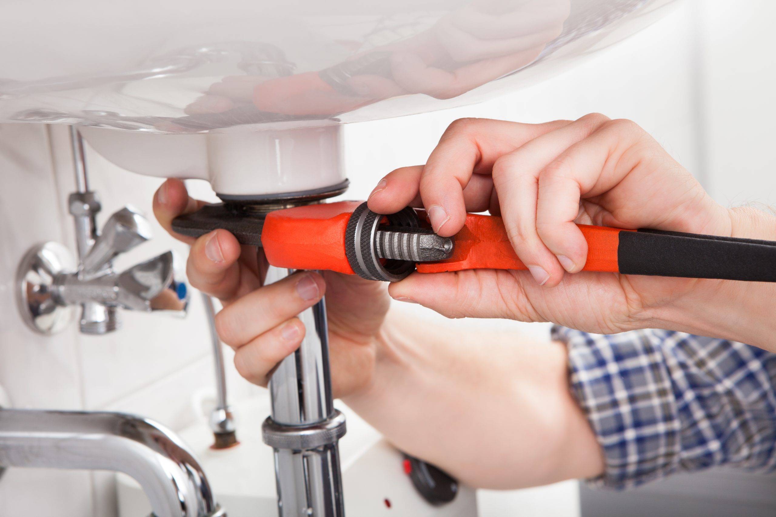 Young Plumber Fixing A Sink In Bathroom